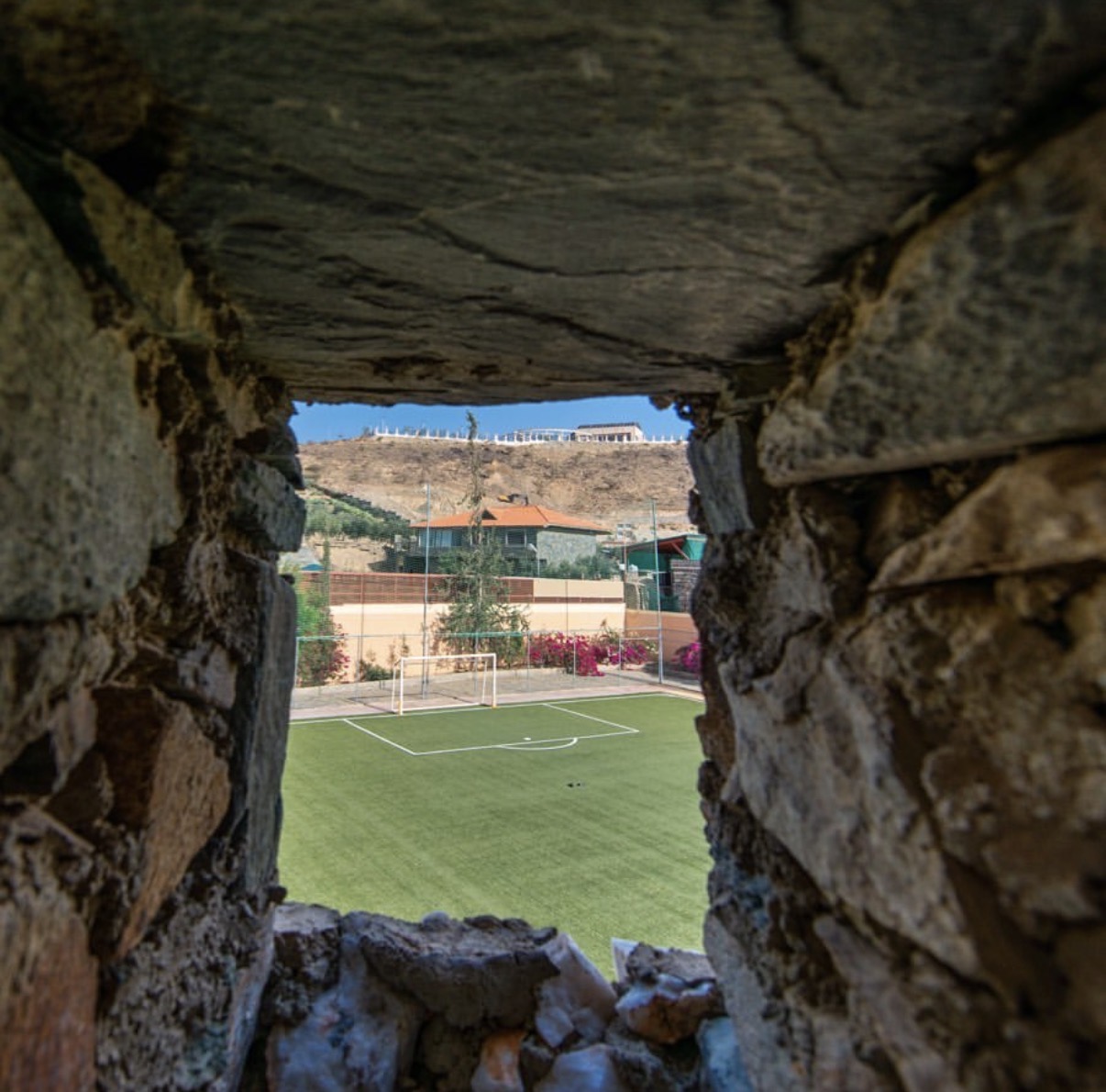 Green field seen through a stone wall opening